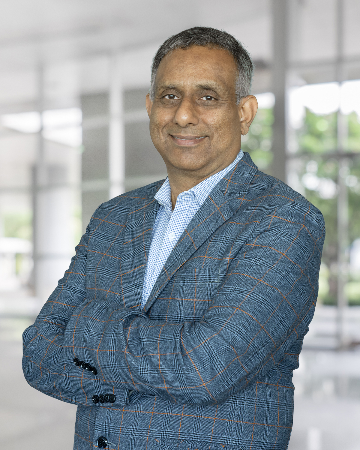 Portrait of Girish P. Kamala, Sr. Director and Country Head Automotive Sales at Infineon Technologies India, with arms folded, wearing a blue checked blazer and light shirt